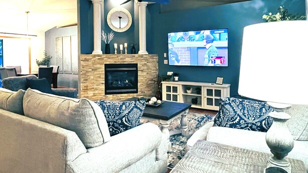 A living room with a fireplace, a ceiling fan, a television, and a coffee table.