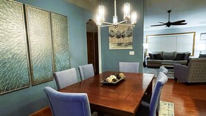 A dining area with a wooden table and chairs, a chandelier, and artwork on the walls.