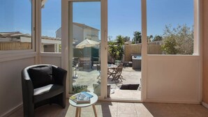 A sunlit room with a glass door leading to an outdoor patio area.
