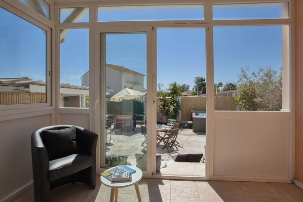 Una habitación iluminada por el sol con un ventanal de vidrio que da a un patio exterior.