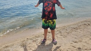 A person standing on a sandy beach with a clear view of the sea and sky.