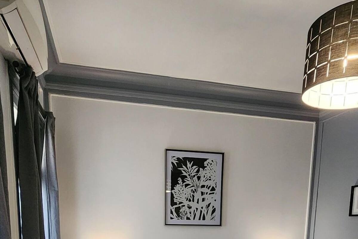 Ein Schlafzimmer mit Bett, zwei Nachttischen, einem Kopfteil, einem Wandbild und einem Fenster mit Vorhängen.