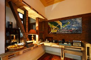 A rustic kitchen with wooden beams, a painting of a sailboat, and various kitchen appliances. - CASA LUCRECIA (Santiago)