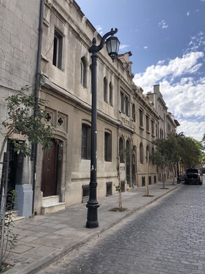 A cobblestone street lined with historic buildings featuring arched windows and a traditional street lamp. - CASA LUCRECIA (Santiago)