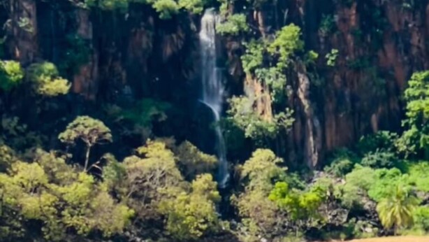 A coastal landscape with a waterfall, dense greenery, and a sandy beach. - Pousada Visual do Porto (Fernando de Noronha)