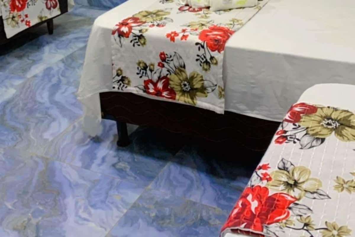 A bedroom with two beds, a TV mounted on the wall, and a wooden door.
