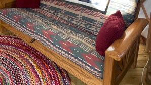 Ein gemütliches Interieur mit einer Holz-Couch, einem gemusterten Teppich und einem gerahmten Bild an der Wand.