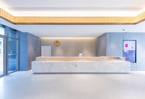 Un área de recepción de diseño moderno, con mostrador de recepción, pantalla digital y reloj de pared.
