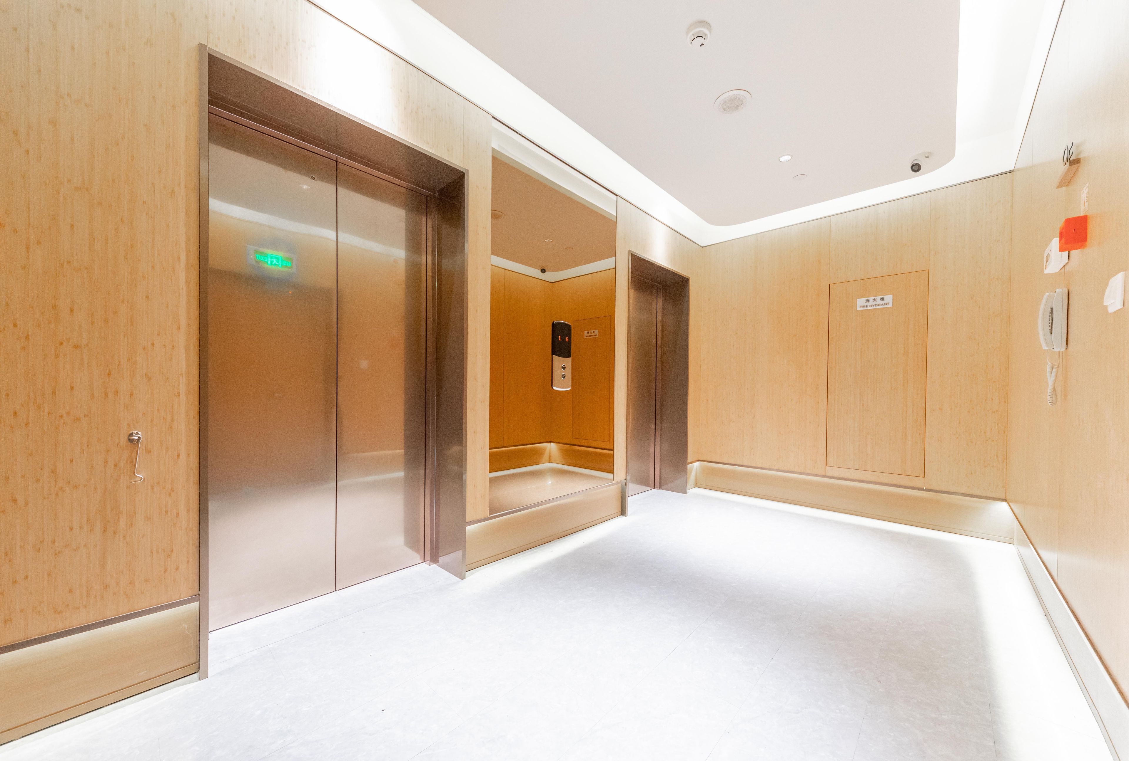 Área de elevador moderna, com planta baixa visível, sinalização de saída de emergência e identificação de hidrante.
