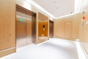 A modern elevator area with a clear floor plan, emergency exit sign, and a fire hydrant sign. - Ji Hotel (Hangzhou)