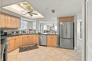 Una cocina moderna con armarios de madera, electrodomésticos de acero inoxidable y un ventilador de techo.