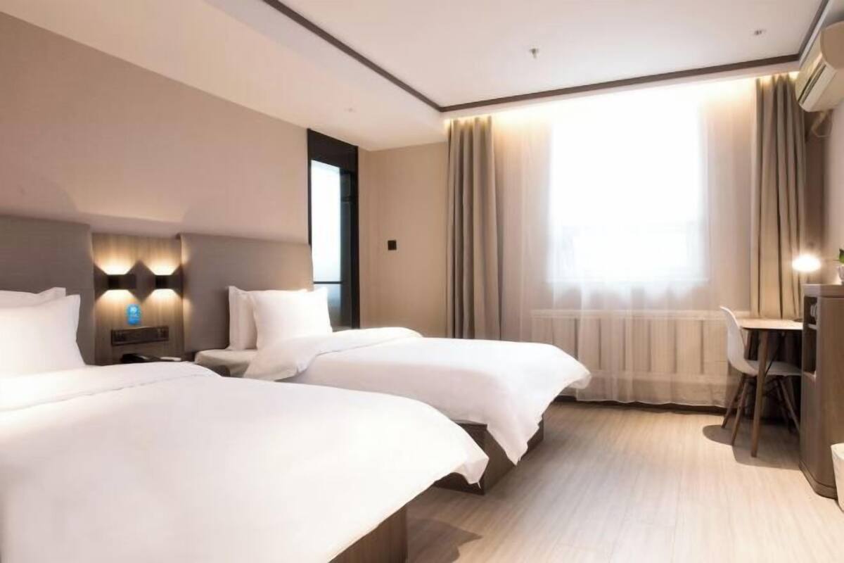 A hotel room with two beds, a desk, and a chair.