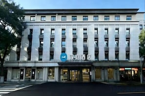 Un hôtel moderne, reconnaissable à son enseigne bien visible, avec de nombreux étages et un passage pour piétons devant l’entrée.