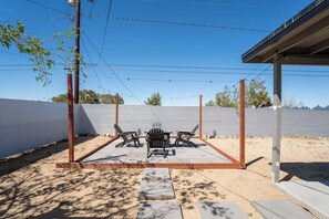 An outdoor patio area with a metal table and chairs, surrounded by a low concrete wall.