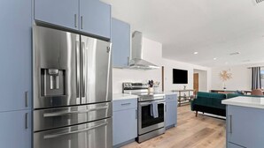 A modern kitchen with stainless steel appliances, a built-in oven, and a dining area with a green sofa.