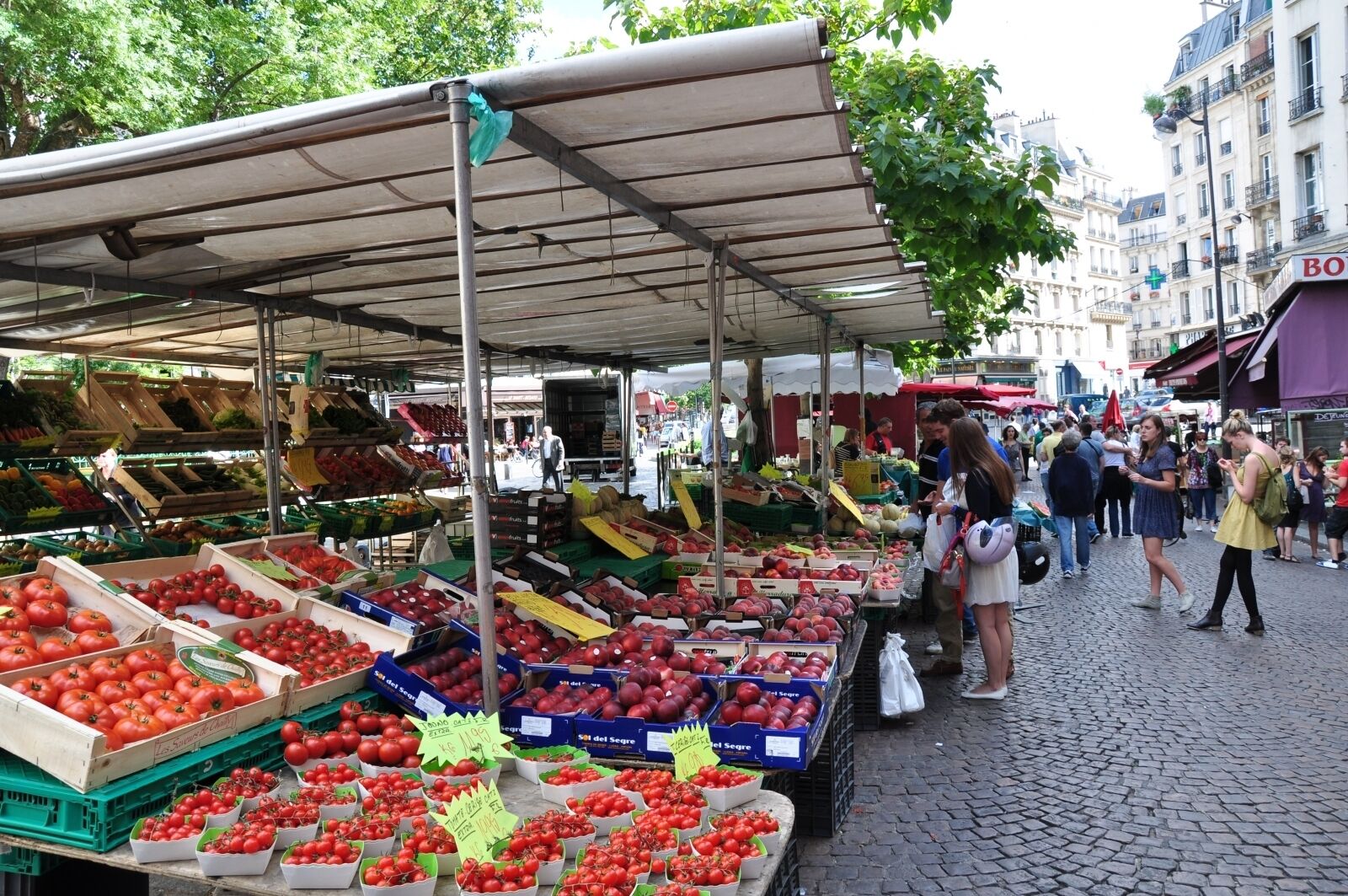 An outdoor market with various stalls selling fresh produce.