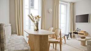 A modern living room with a round wooden table, two wicker chairs, a sofa, and a TV mounted on the wall. - Amazing Apt Prestige at Mouffetard Paris 5 (Paris)