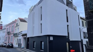 A modern building with a black and white facade, a visible entrance, and a red arrow pointing to the door. - Living PDL 1, new and contemporary apartment in the center of Ponta Delgada (Ponta Delgada)