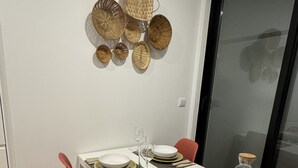 A dining area with a white table set for four, red chairs, and a wall-mounted basket collection. - Living PDL 1, new and contemporary apartment in the center of Ponta Delgada (Ponta Delgada)