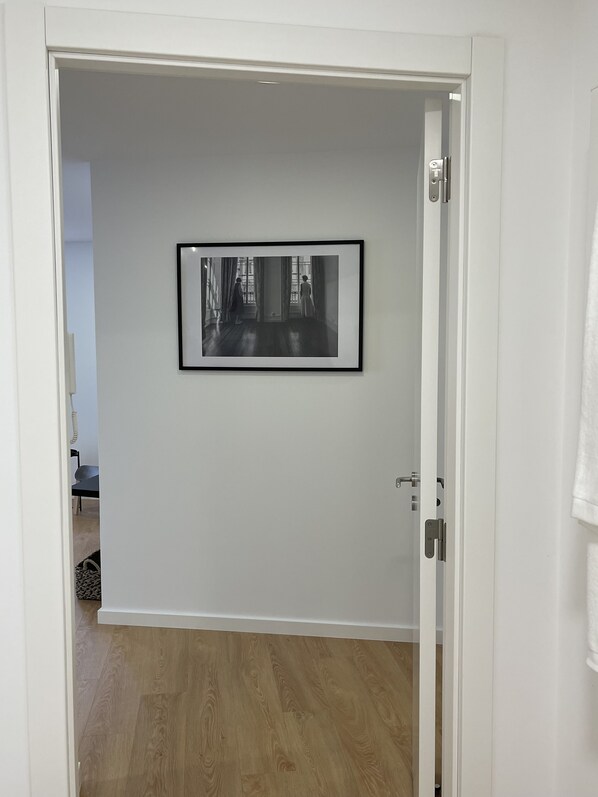 A room with a framed black and white photograph on the wall, a wooden floor, and a white door. - Living PDL 1, new and contemporary apartment in the center of Ponta Delgada (Ponta Delgada)