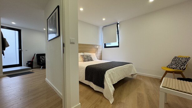 A modern bedroom with a bed, a chair, and a small table. - Living PDL 1, new and contemporary apartment in the center of Ponta Delgada (Ponta Delgada)