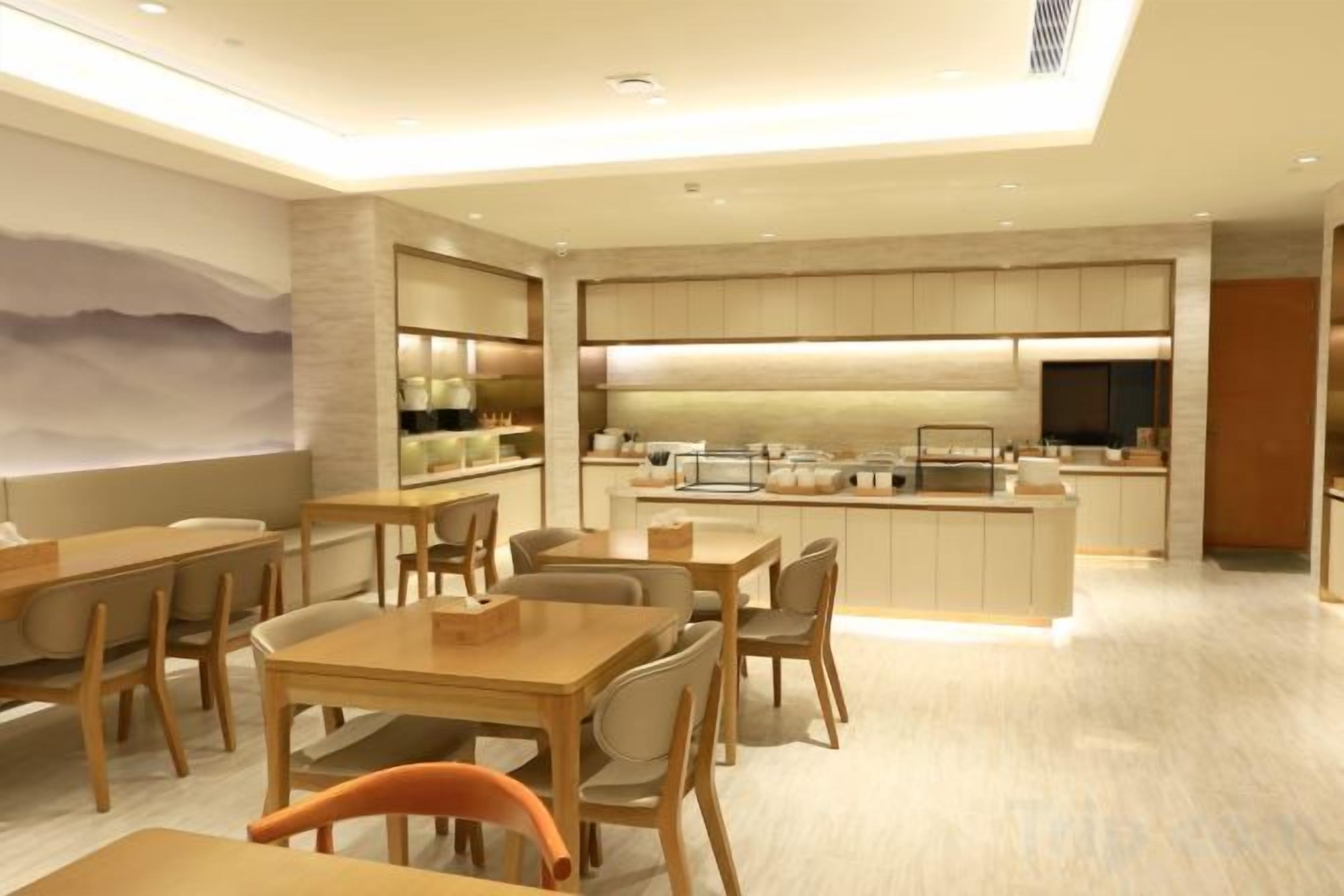 Un espace de restauration moderne avec des tables et des chaises, une cuisine en arrière-plan et une grande fenêtre offrant une belle vue.