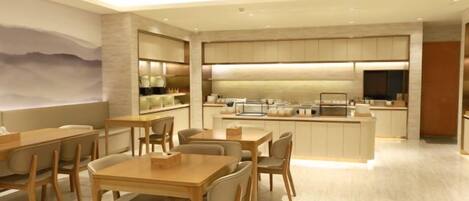 Un espace de restauration moderne avec des tables et des chaises, une cuisine en arrière-plan et une grande fenêtre offrant une belle vue.
