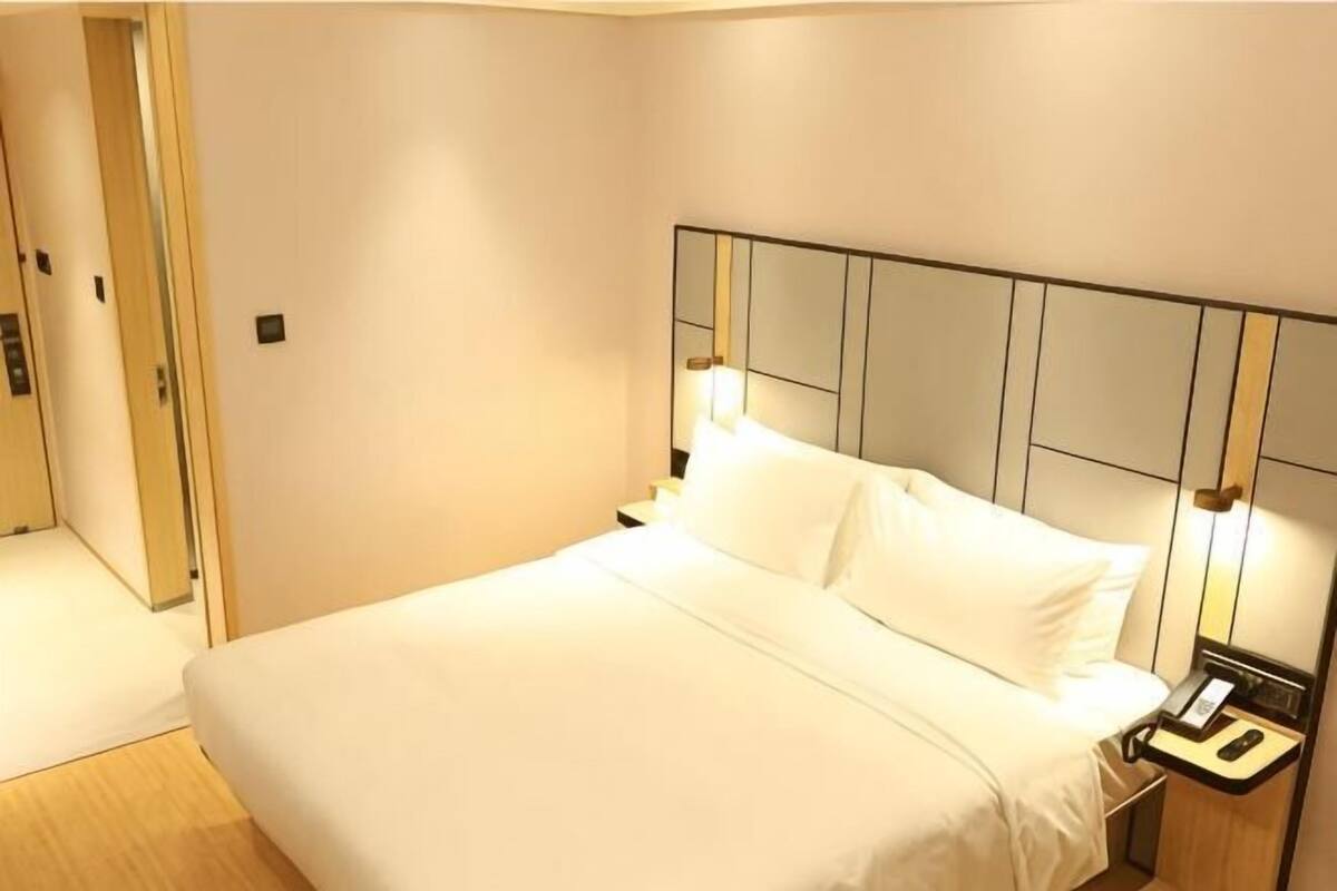 A hotel room with a bed, bedside tables, and a door.