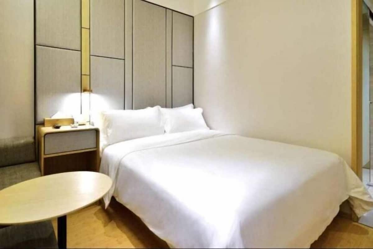 A hotel room with a bed, bedside table, lamp, and a small round table.