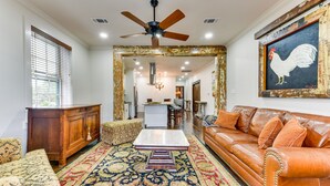 A living room with a brown leather sofa, patterned ottoman, and a large rug. - Chic Louisiana Retreat - Balcony & River Views! (New Roads)