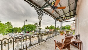 A balcony with a view of a street, a clock, and a building in the background. - Chic Louisiana Retreat - Balcony & River Views! (New Roads)