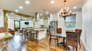 A spacious kitchen with a central island, stainless steel appliances, and a chandelier. - Chic Louisiana Retreat - Balcony & River Views! (New Roads)