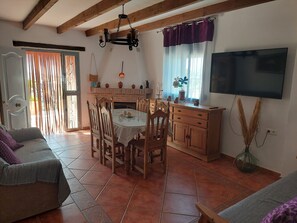 Un comedor con una mesa y sillas, una chimenea y un televisor montado en la pared.