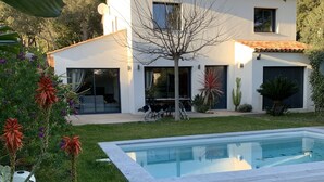 Et moderne hus med swimmingpool, omgivet af en velplejet have og en patio.