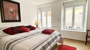 A bedroom with a bed, pillows, a nightstand, a lamp, and a window.