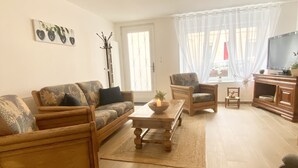 A living room with a sofa, armchairs, a coffee table, and a TV.
