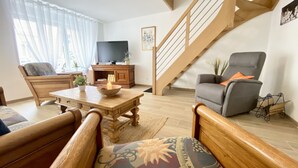 A living room with a wooden coffee table, a sofa, a TV, and a staircase.