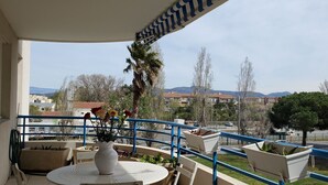 A balcony with a white table and chairs, a vase with flowers, and a view of buildings and trees in the background. - Fréjus Plage, Le Sextant, Large T2 of 52m2, 3/4 people, swimming pool, large balcony, WIFIair-conditioned living room, 400m from the beach (Fréjus)