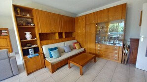 A living room with a sofa, wooden cabinets, a coffee table, and a glass display cabinet. - Fréjus Plage, Le Sextant, Large T2 of 52m2, 3/4 people, swimming pool, large balcony, WIFIair-conditioned living room, 400m from the beach (Fréjus)