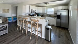 A modern kitchen with white cabinets, a stainless steel refrigerator, and a wooden island with bar stools.