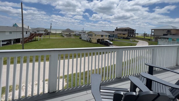 A coastal residential area with houses, a grassy lawn, and a clear sky.