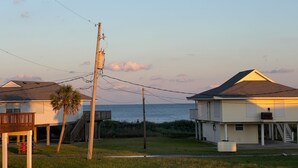 A coastal residential area with houses, a wooden utility pole, and a view of the ocean.