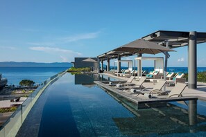 A infinity pool with lounge chairs and umbrellas, overlooking the sea. - Secrets Bahia Mita Surf & Spa (Punta de Mita)