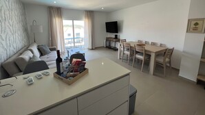 A modern living room with a sofa, a dining table with chairs, a TV mounted on the wall, and a balcony with a table and chairs. - Spectacular views and location (Salir do Porto)