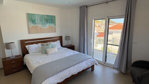 A bedroom with a bed, nightstands, a painting, and a view through a sliding door. - Spectacular views and location (Salir do Porto)