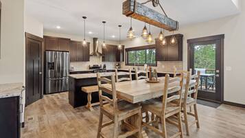 A modern kitchen with dark wood cabinets, stainless steel appliances, and a wooden dining table with chairs.