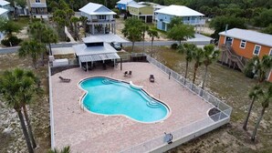 A swimming pool surrounded by a fenced patio area with lounge chairs and a covered seating area. - Wait' N Sea - Vacation Home Steinhatchee Florida (Steinhatchee)