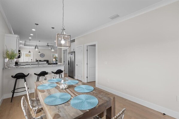 A modern kitchen with white cabinets, a stainless steel refrigerator, and a hanging light fixture. - Wait' N Sea - Vacation Home Steinhatchee Florida (Steinhatchee)