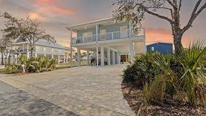 A two-story building with a balcony, surrounded by palm trees and a paved walkway. - Wait' N Sea - Vacation Home Steinhatchee Florida (Steinhatchee)
