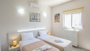 Une chambre d’hôtel avec deux lits, une fenêtre donnant sur un paysage agréable, un appareil de climatisation et des œuvres d’art accrochées aux murs.